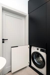 a washing machine in a bathroom with a white door at Łódź Prestige Suites - 64m2, Parking, Office Room - by Rentujemy in Łódź