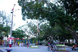 un parque con gente sentada en bancos y un parque infantil en Casa em Itaipuaçu na Praça do Ferrerinha. en Maricá