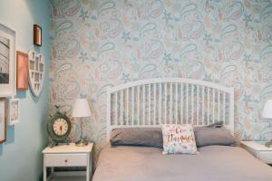 1 dormitorio con cama blanca y pared con papel pintado en Entertainer's Estate en Ballyeaston