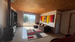 sala de estar con sofá y TV en vista al mar curanipe cabaña/casa, en Curanipe