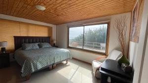 a bedroom with a bed and a large window at vista al mar curanipe cabaña/casa in Curanipe