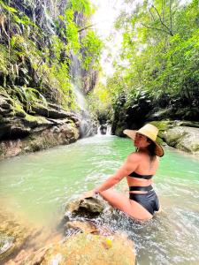 a woman sitting on a rock in a river at Finca Ecoturistica Xtremly 