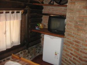 a television sitting on top of a refrigerator next to a brick wall at SENCILLAMENTE CABAÑAS in Casa Grande