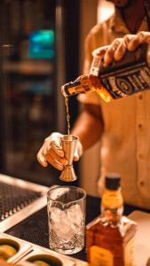 un hombre está vertiendo una bebida en un vaso en Anacardier Privé Hotel, en Atins