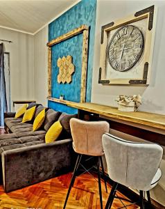 a living room with a couch and a clock on the wall at Apartman Marijana in Novi Sad