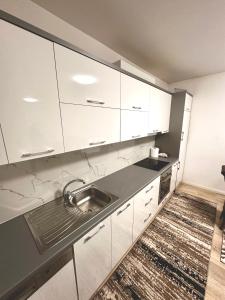 a kitchen with white cabinets and a sink at Lovely Family Apartment in Ferizaj