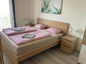 a bedroom with a bed with pink pillows on it at Panoráma Gold Wellness Apartman in Siófok +29 photos