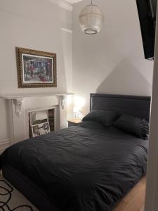 a bedroom with a black bed and a picture on the wall at Kemp Town apartment in Brighton & Hove