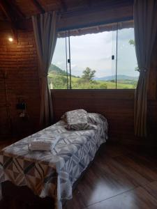 a bed in a room with a large window at Pousada Sons do Silêncio in Socorro