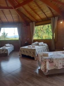 a room with two beds and a large window at Pousada Sons do Silêncio in Socorro