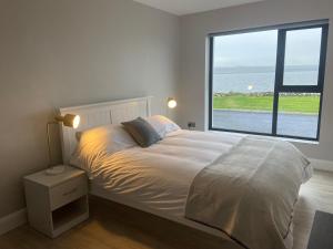 a bedroom with a bed and a large window at Spectacular ocean views & minutes to Cliffs- Clahane Shore Lodge in Liscannor