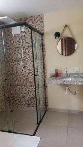 a bathroom with a shower with a mirror and a sink at Pousada Sons do Silêncio in Socorro