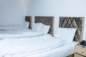 2 camas en una habitación con almohadas blancas en Regal Residency en Rawalpindi