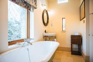 a bathroom with a tub and a sink and a window at Kinkell Cottage in Dingwall