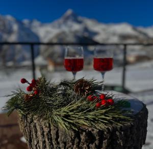 two glasses of red wine sitting on a table with christmas decorations at Vista cottage in Stepantsminda
