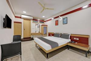 a bedroom with a bed and a desk and a tv at Collection O Sri Sai Ram Suites in Bangalore