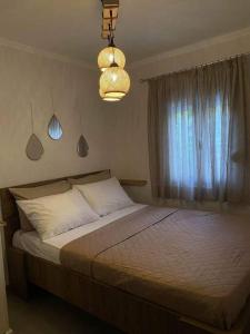 a bedroom with a bed with a window and a chandelier at D & A house 150m from Chalandri metro station in Athens
