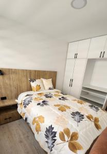 a bedroom with a bed with a leaf printed comforter at la terraza departamentos 301 in Cuenca