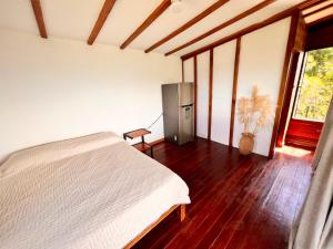 1 dormitorio con 1 cama blanca y nevera en Ecohotel Sereni Norcasia, en Samaná