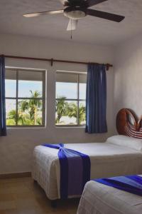 a bedroom with two beds and a window with palm trees at Hotel Quijote Inn in Mazatlán