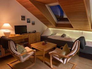ヴィリンゲンにあるFeWo Gipfelglückのベッド、テレビ、椅子が備わる客室です。