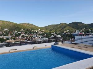 a swimming pool on the roof of a building with mountains at Departamento San José IV- Villa Carlos Paz in Villa Carlos Paz