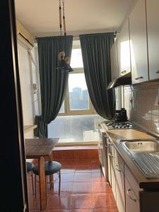a kitchen with green curtains and a table and a window at Downtown Studio Calea Victoriei in Bucharest