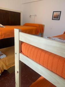 zwei Betten in einem Zimmer mit orangefarbenen Laken in der Unterkunft Che Neco in Necochea