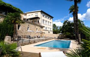 a building with a swimming pool in front of a building at Domaine de la Pinède in Aubenas
