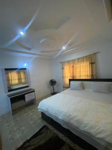 a bedroom with a white bed and a television at Enugu Apartments in Enugu