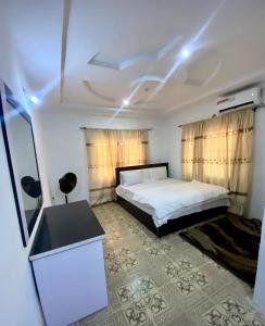 a bedroom with a bed and a desk and curtains at Enugu Apartments in Enugu