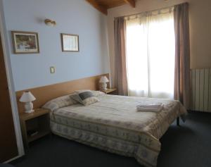 a bedroom with a bed and a large window at Hotel Sehuen in Río Gallegos