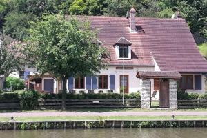 una casa con un árbol frente a un río en Gîte du Flotteur, en Chevroches