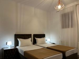 a bedroom with two beds and a chandelier at Pensiunea Le Patrick in Afumaţi