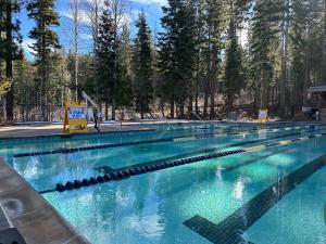 a large swimming pool with blue water and trees at Lofty Retreat, Condo in Northstar in Truckee
