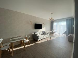sala de estar con sofá, mesa y sillas en Apartamentai Ornamentai en Druskininkai
