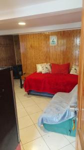1 dormitorio con 1 cama con manta roja en Departamentos Buena Vista, en El Quisco