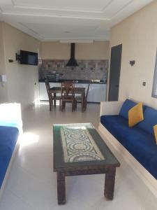 a living room with a blue couch and a table at Amouage résidence 3 in Sidi Ifni