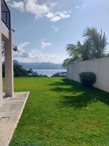 a grassy yard with a fence and palm trees at Arenal Vistas del Paraiso in Nuevo Arenal