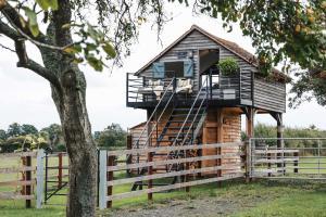 a tree house in a field with a fence at The Treehouse at Humblebee Hall in Worcester