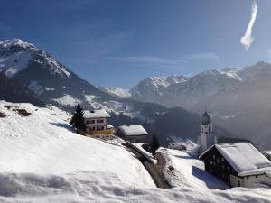 a snow covered mountain with a building and a church at Sonnegg in Fontanella