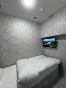 a bedroom with a bed with a tv on the wall at ReveL HoteL in Tashkent