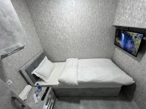 Kleines Zimmer mit einem Bett und einem TV an der Wand in der Unterkunft ReveL HoteL in Taschkent