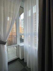 um quarto com cortinas brancas e uma grande janela em HAMSTER APART em Kiev