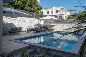 a swimming pool with chairs and umbrellas next to a building at Adam apartments in Stobreč