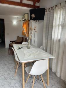 una mesa blanca con sillas blancas y un jarrón con flores en Apartamento Remansum en Santa Rosa de Calamuchita