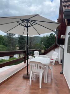 a white table and chairs with an umbrella on a balcony at Apartamento Remansum in Santa Rosa de Calamuchita