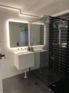 a bathroom with a sink and two mirrors and a shower at Luxury inner-west flat w/ breakfast and coffee included! in Sydney