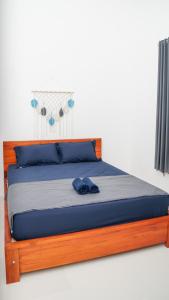 een bed met een houten frame en blauwe kussens bij Wangi Homestay in Banyuwangi