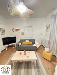 ein Wohnzimmer mit einem Sofa und einem Tisch in der Unterkunft Ulyssee Seh’Loué in Saint-Brieuc